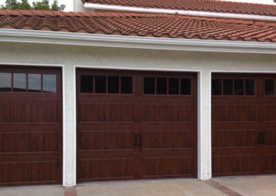 Spanish-style home with rich mahogany garage doors, classic window panels, and terra cotta tile roofing.